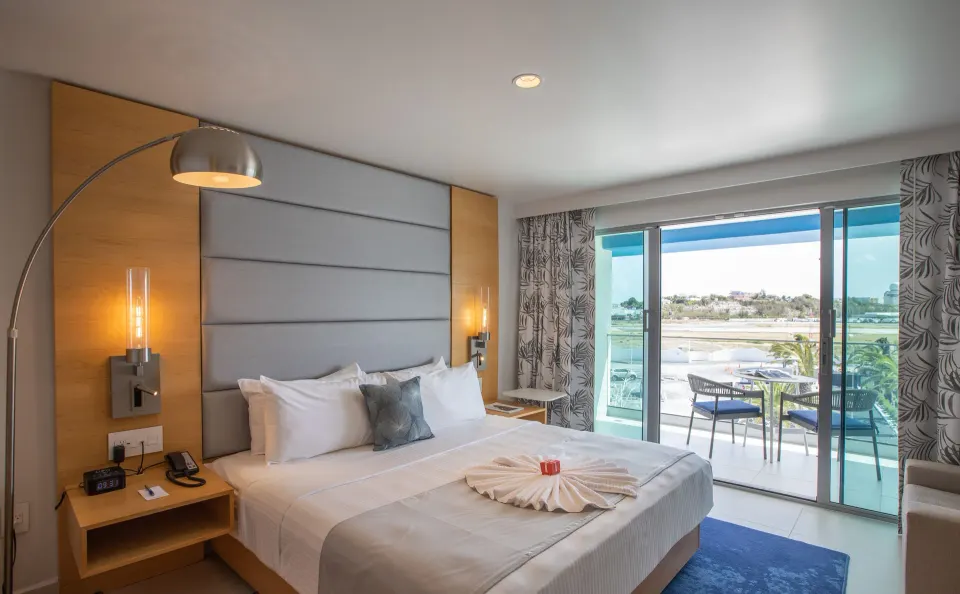 Runway View Guestroom king bed and balcony at The Morgan Resort Spa Village.