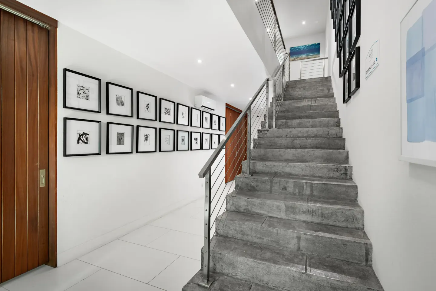 Interior stairway with framed artwork and white walls at The Oasis at Grace Bay.