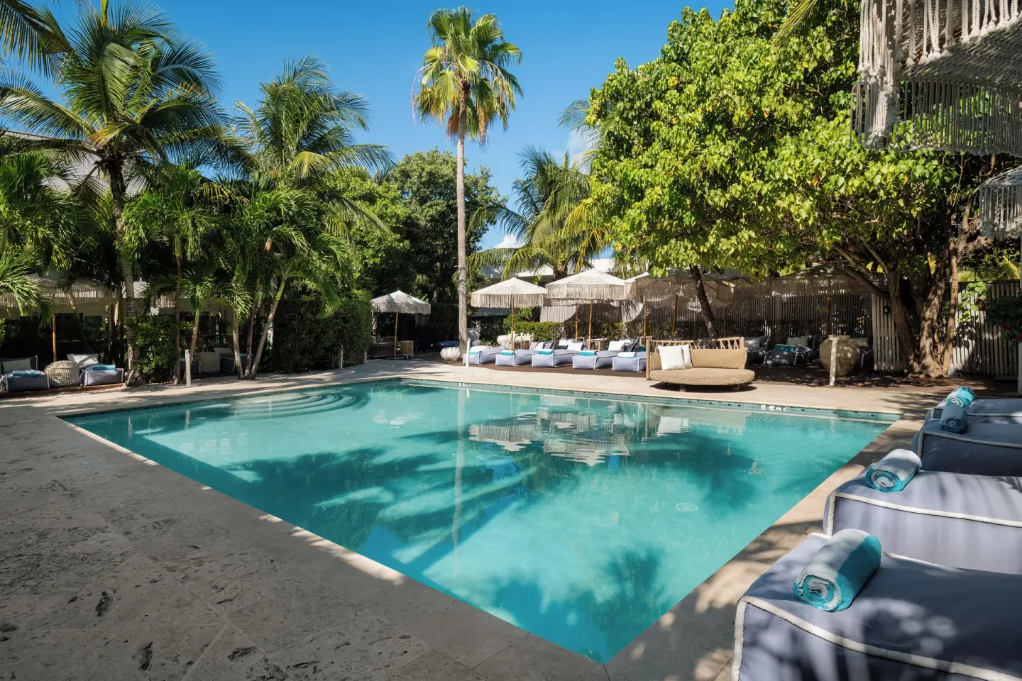 Palm-lined pool deck with daybeds at The Oasis at Grace Bay.