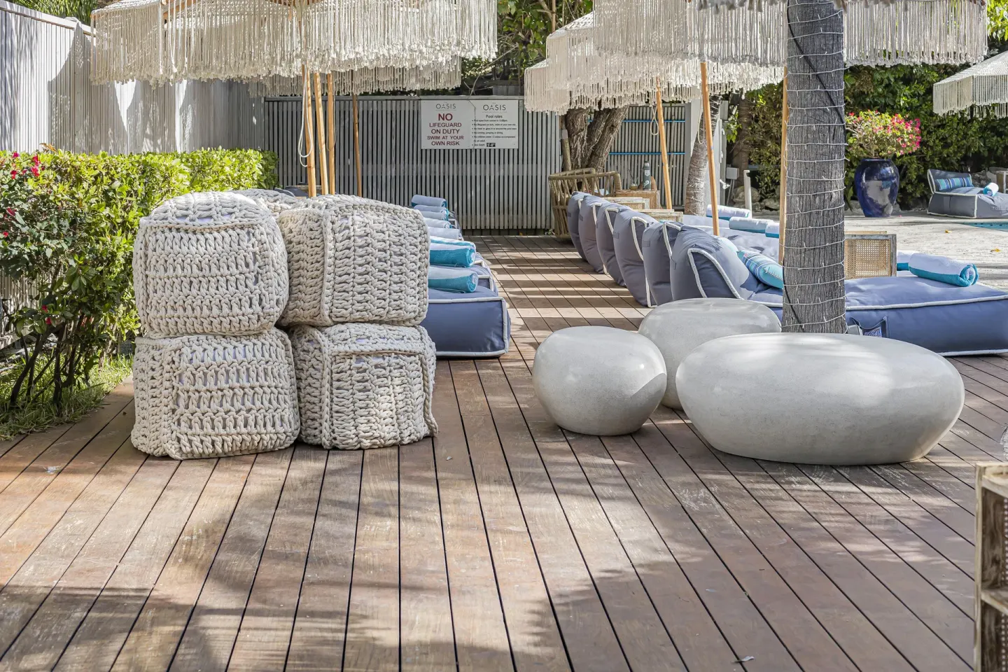 Poolside deck with loungers, umbrellas, and seating at The Oasis at Grace Bay.