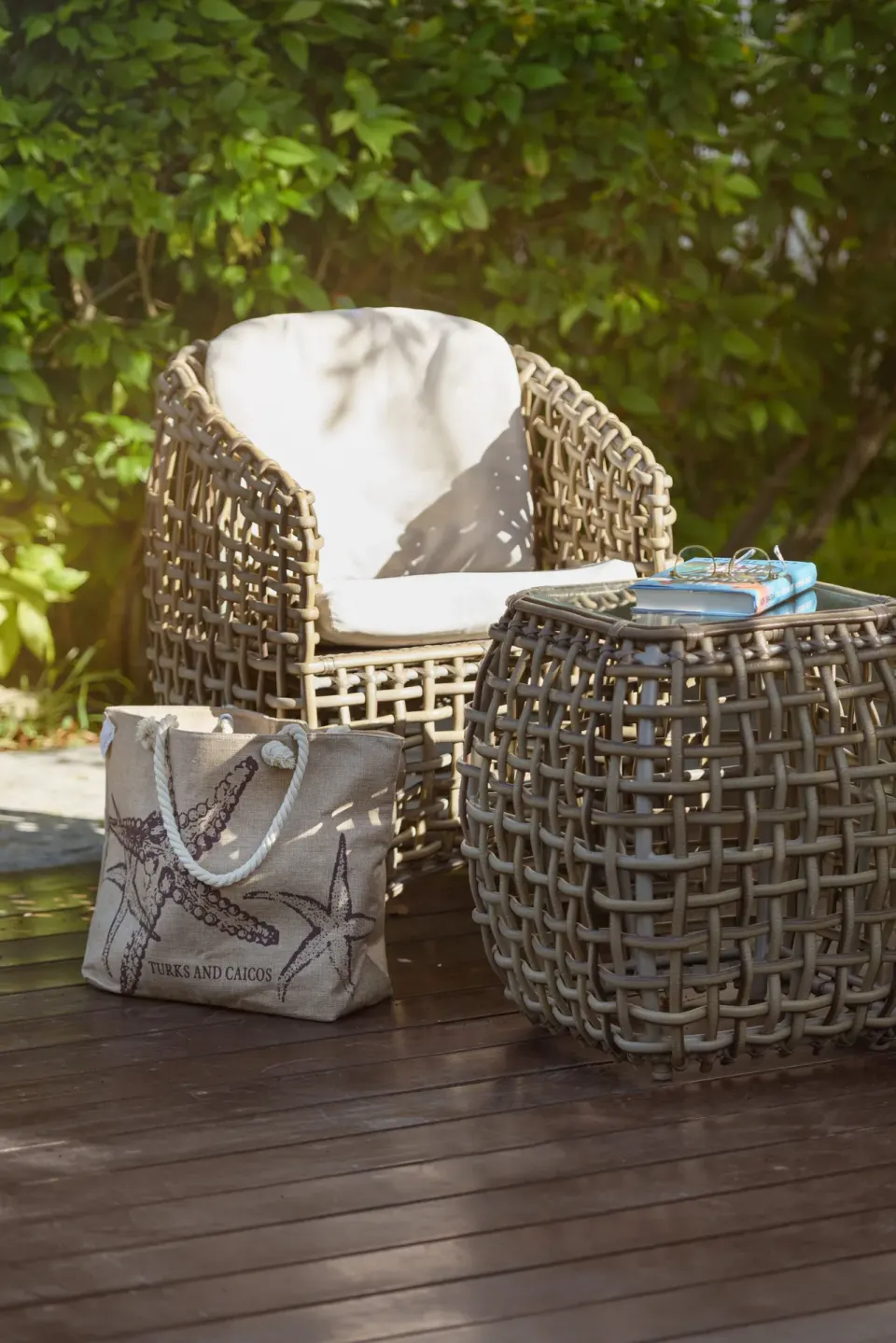 A woven patio chair, side table, and beach tote on a deck at The Oasis at Grace Bay.