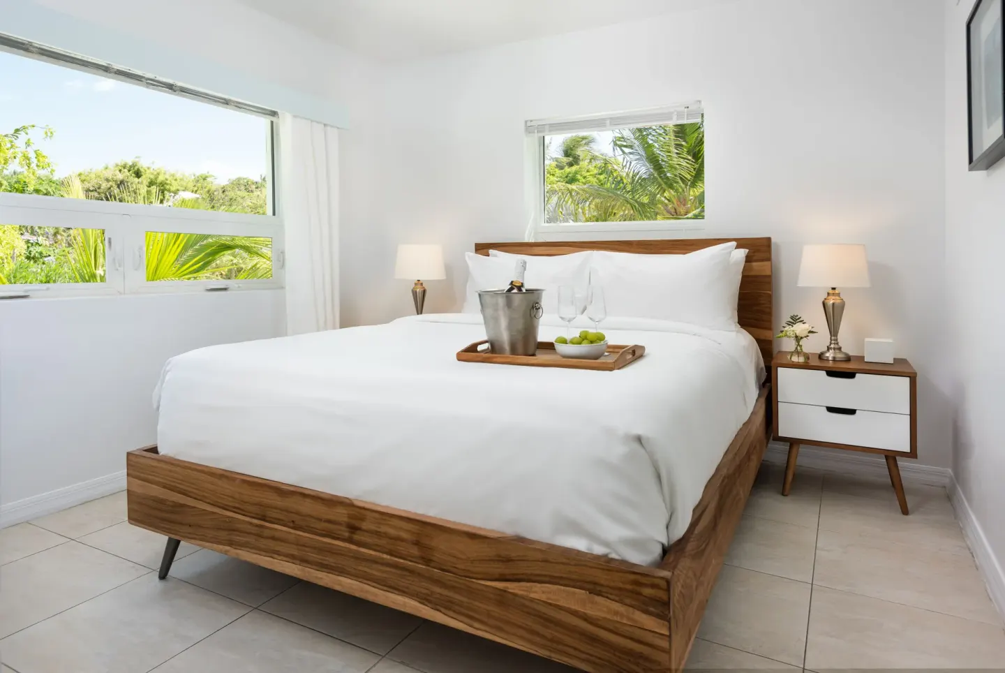 Bedroom with wood-framed king bed, tray, and palm views in a Two Bedrooms Pool Suite at The Oasis at Grace Bay.