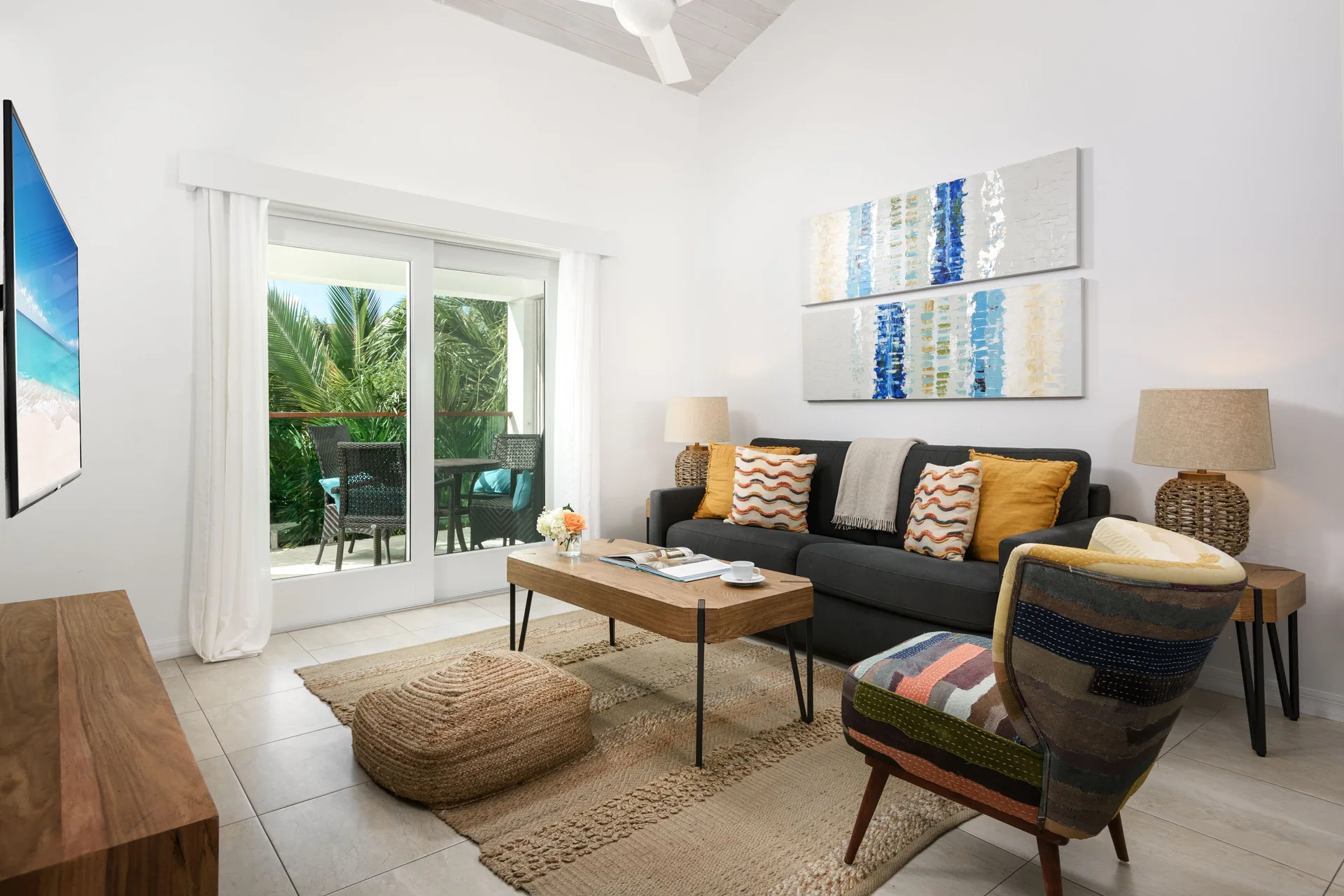 Living room with sofa, colorful chair, coffee table, and balcony doors at The Oasis at Grace Bay.