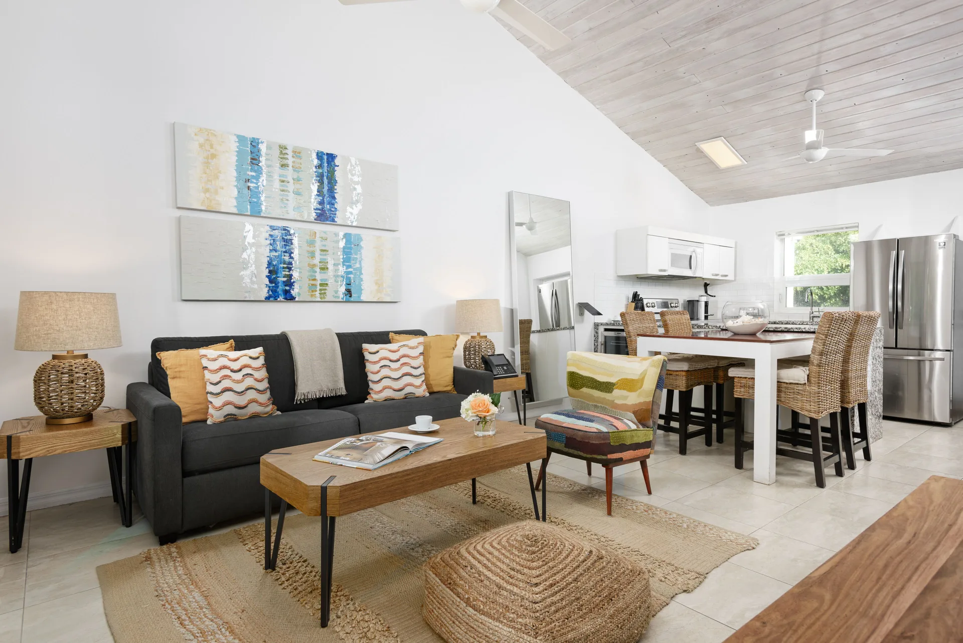 Open living and kitchen area with sofa, island seating, and refrigerator at The Oasis at Grace Bay.
