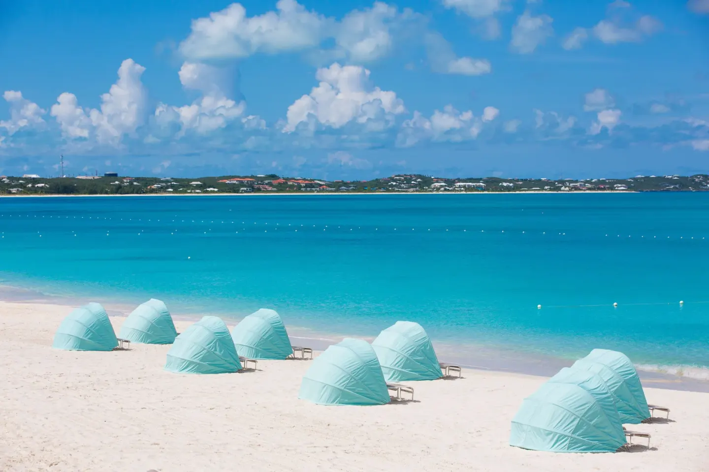 Pale blue beach cabanas facing turquoise water at The Palms Turks and Caicos.
