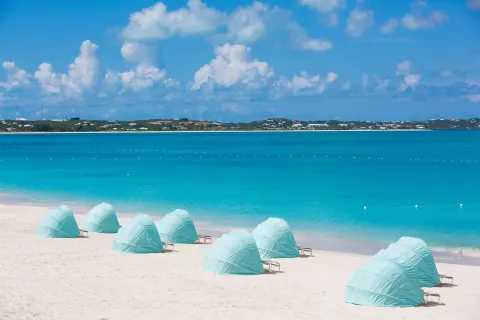 Pale blue beach cabanas facing turquoise water at The Palms Turks and Caicos.