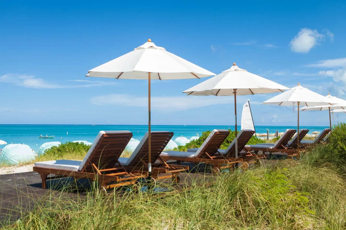 Wood loungers and white umbrellas overlooking the beach at The Palms Turks and Caicos.