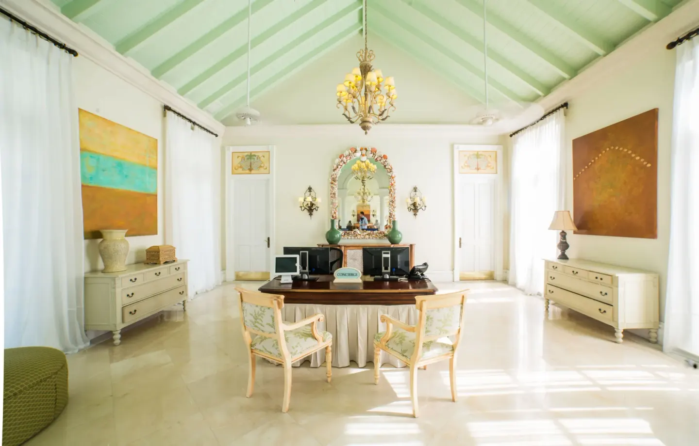 Concierge desk with twin chairs and artwork in the lobby at The Palms Turks and Caicos.