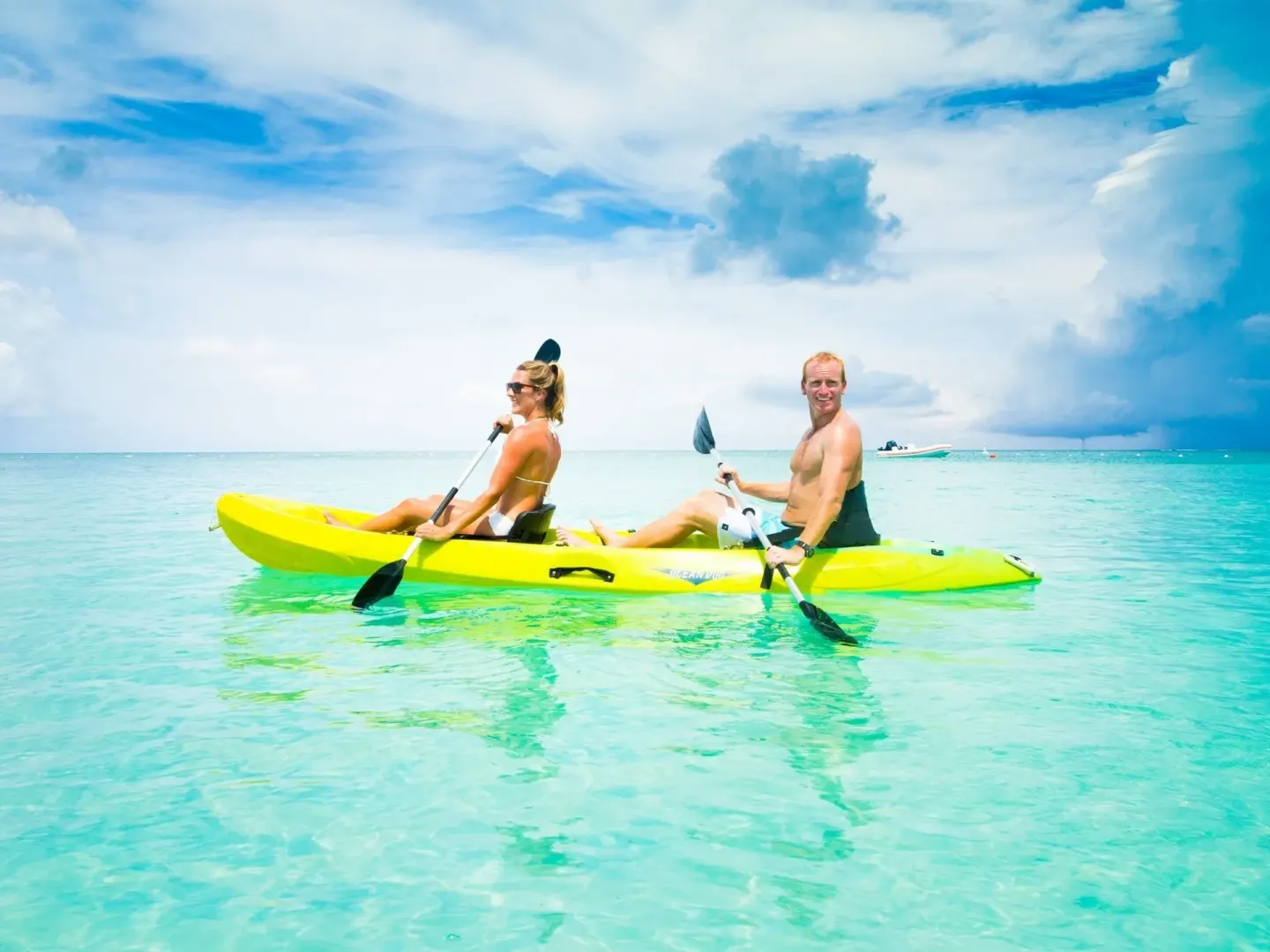 Guests paddle a yellow kayak over clear turquoise water at The Palms Turks and Caicos.