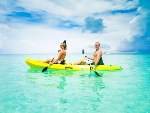 Guests paddle a yellow kayak over clear turquoise water at The Palms Turks and Caicos.