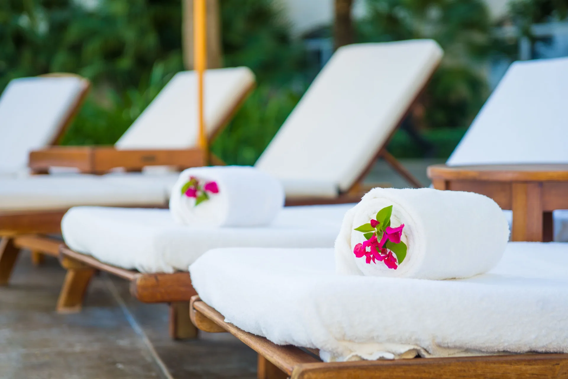 Pool loungers with rolled towels and pink flowers at The Palms Turks and Caicos.