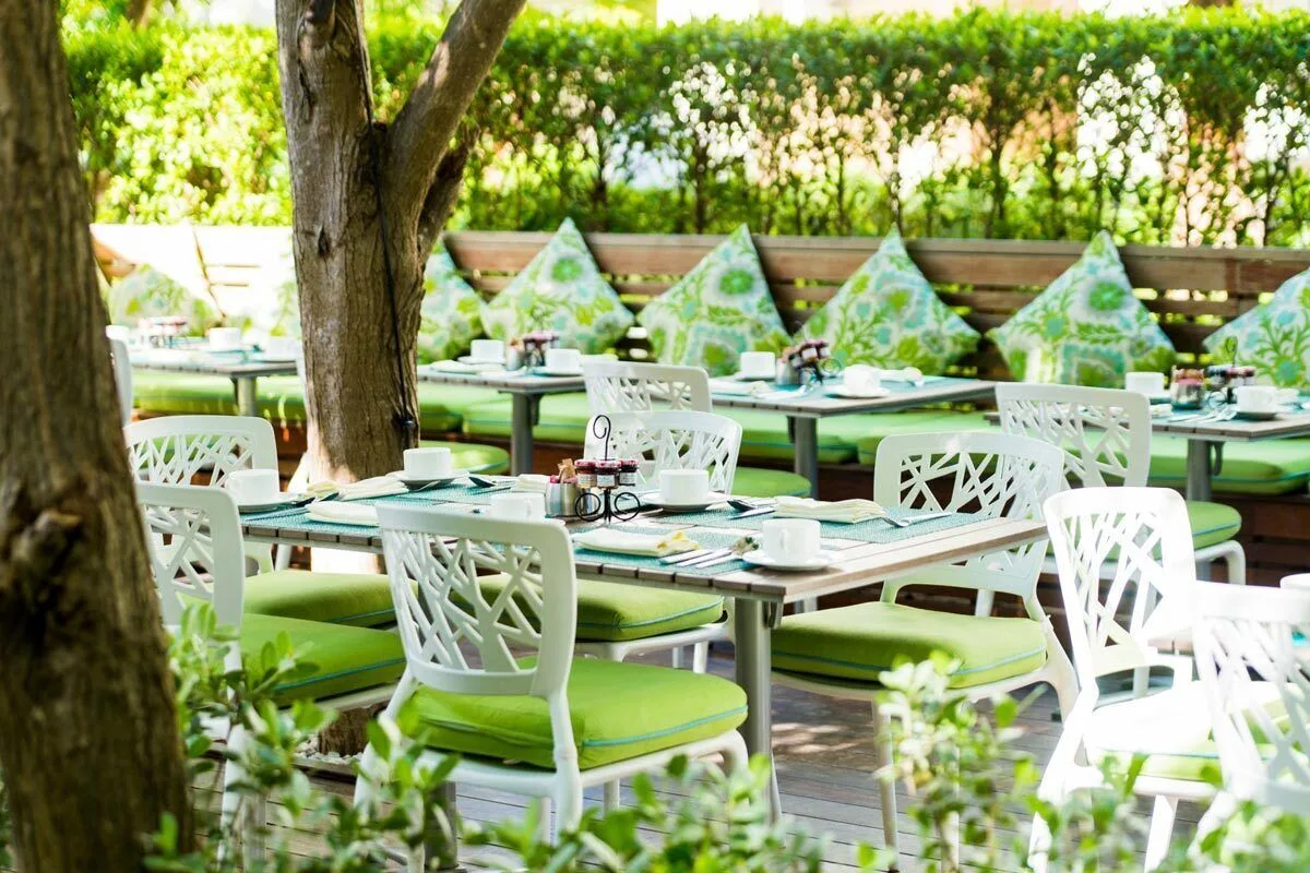 Shaded outdoor dining tables with green cushions are set at The Palms Turks and Caicos.