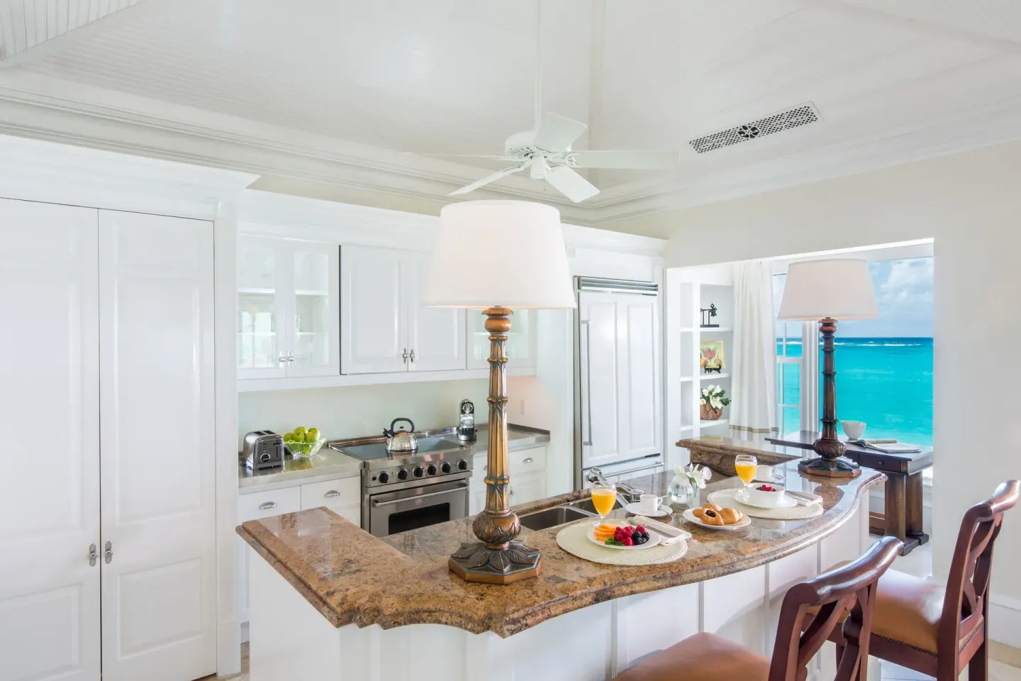 Kitchen island with breakfast set beside ocean-facing windows at The Palms Turks and Caicos.