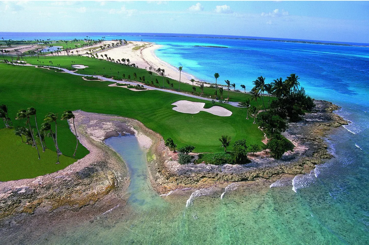 Aerial view of a golf course and bright blue coastline at The Reef at Atlantis.