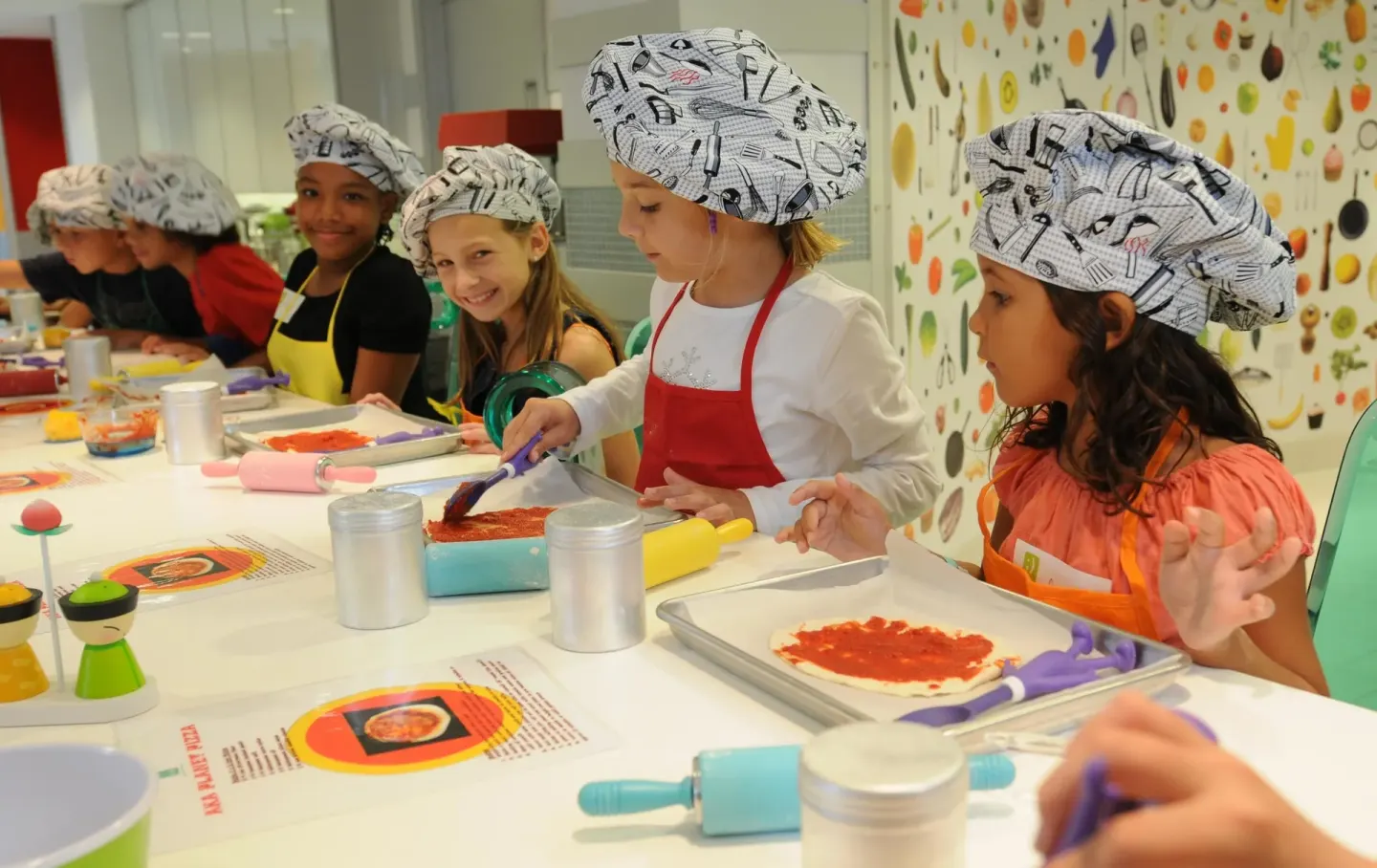 Children in chef hats preparing pizzas during an activity at The Reef at Atlantis.