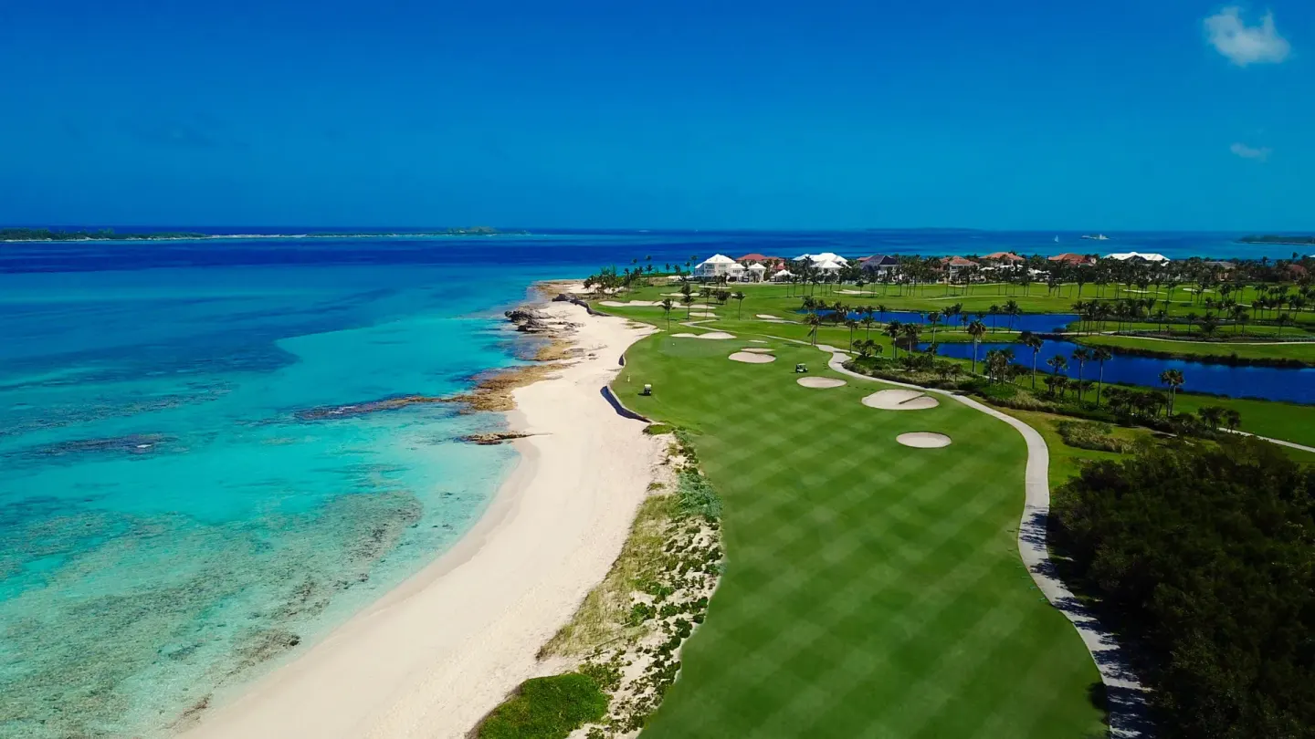 A coastal golf fairway runs beside turquoise ocean near The Reef at Atlantis.