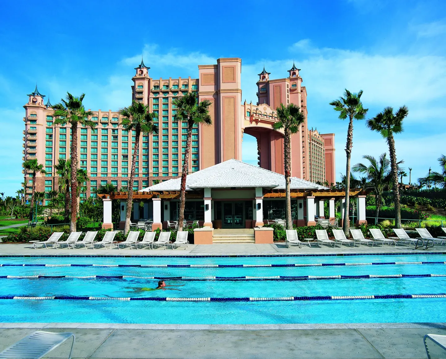 Lap pool, lounge chairs, palms, and resort towers at The Reef at Atlantis.
