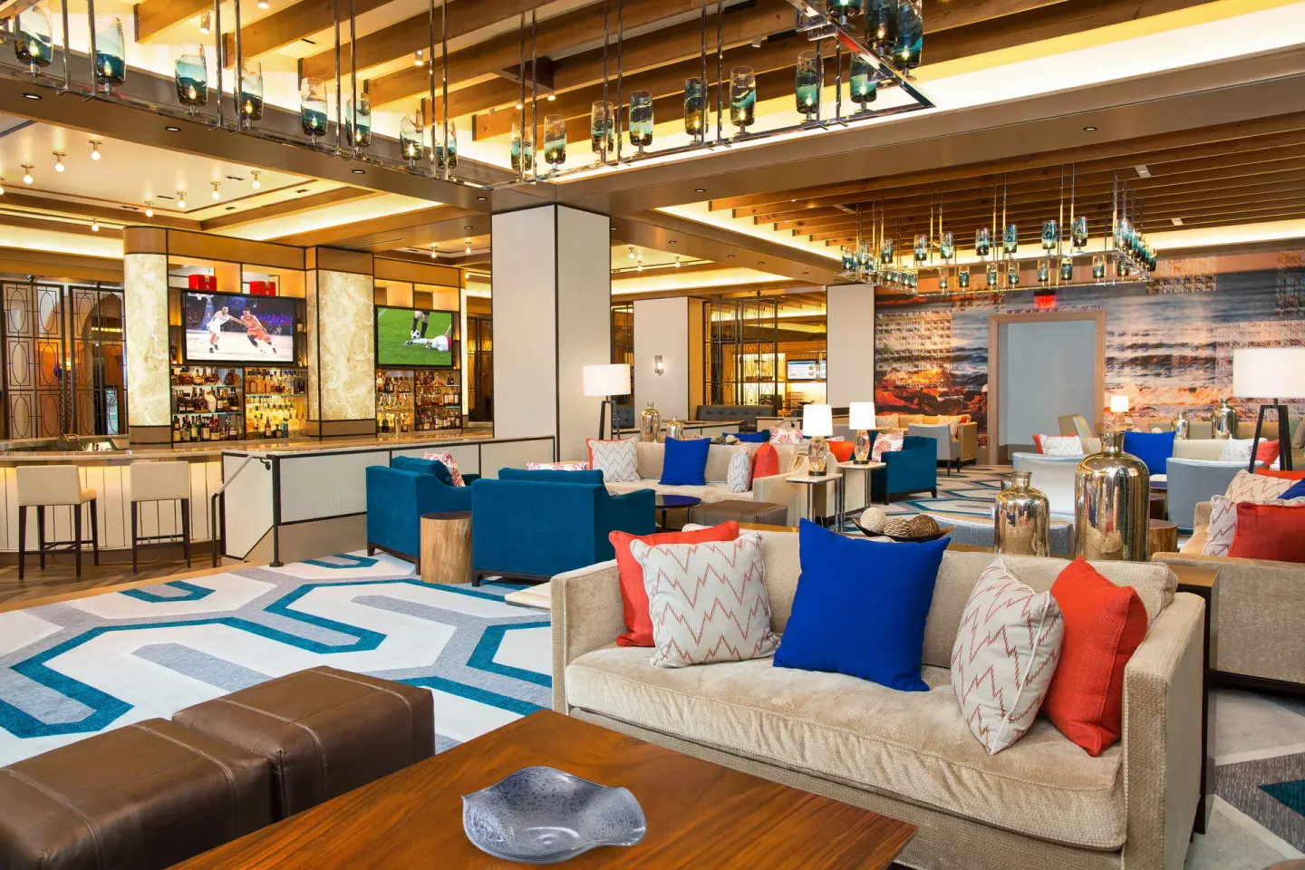 Bright lobby lounge with sofas, patterned carpet, and bar at The Reef at Atlantis.