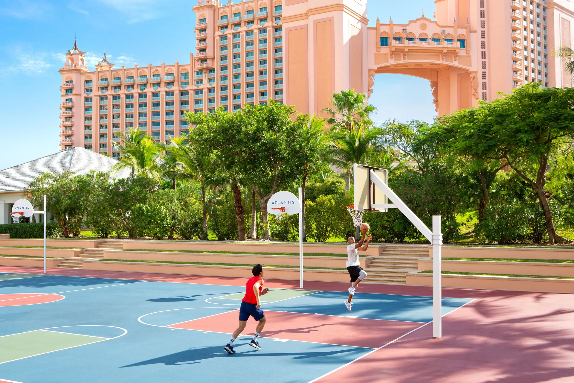 Outdoor basketball court with players and resort towers at The Reef at Atlantis.