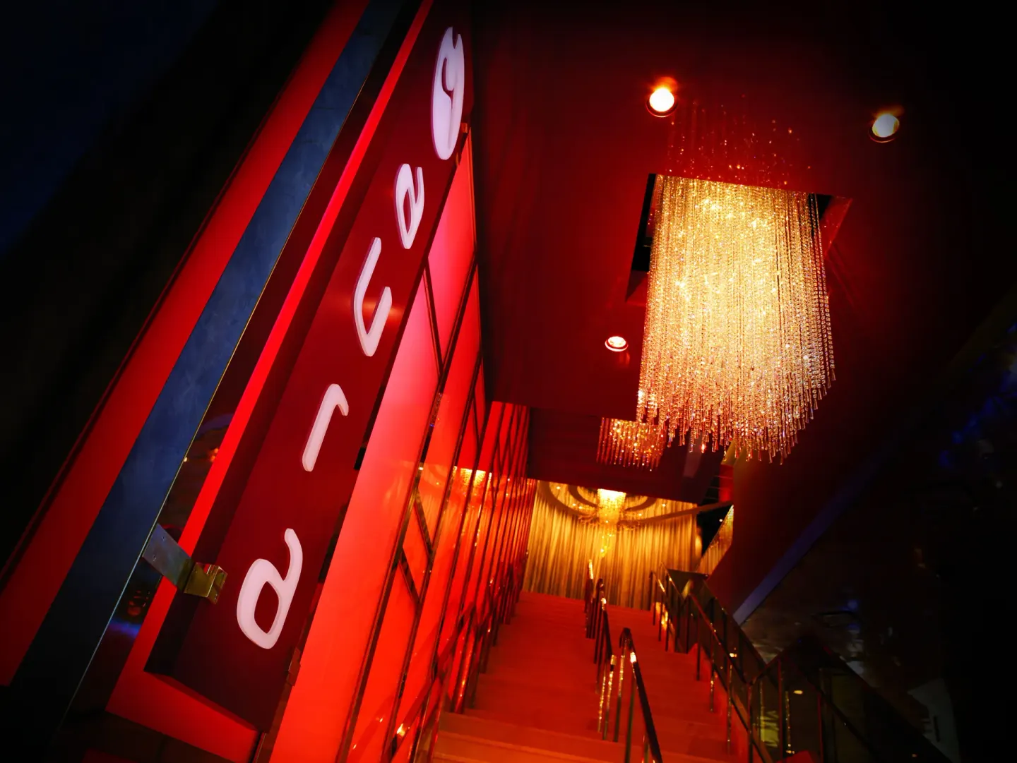 Red-lit staircase and chandelier in a nightlife entrance at The Reef at Atlantis.