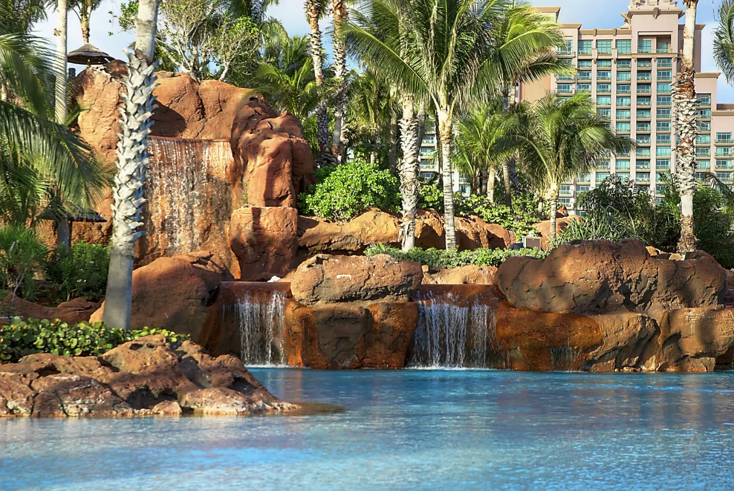 Rock waterfalls, palms, and pool water at The Reef at Atlantis.