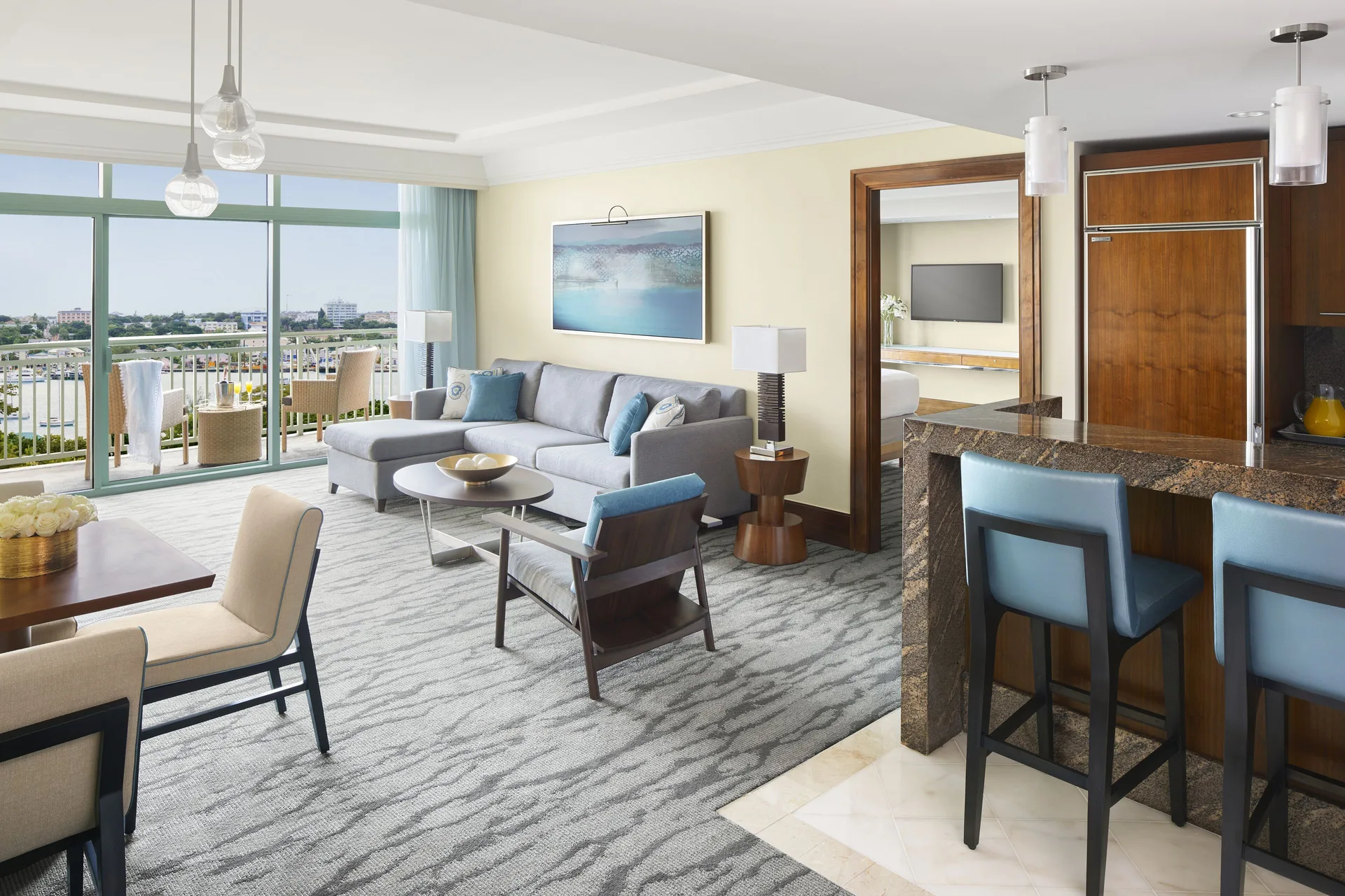 One Bedroom Harbor Suite living area with balcony and kitchenette at The Reef at Atlantis.