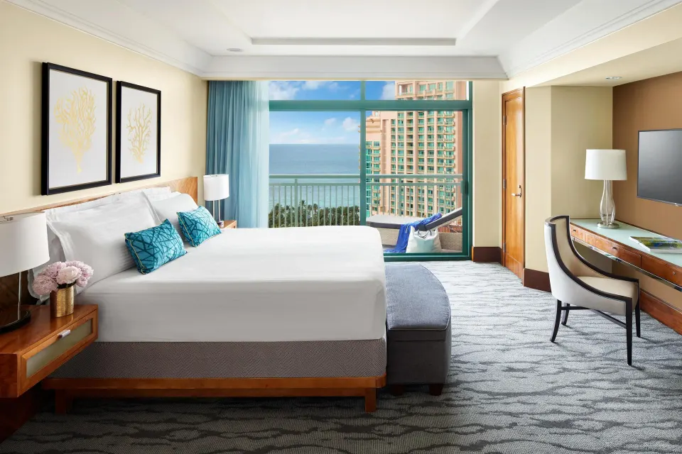 One Bedroom Ocean Suite king bedroom with ocean-facing balcony at The Reef at Atlantis.