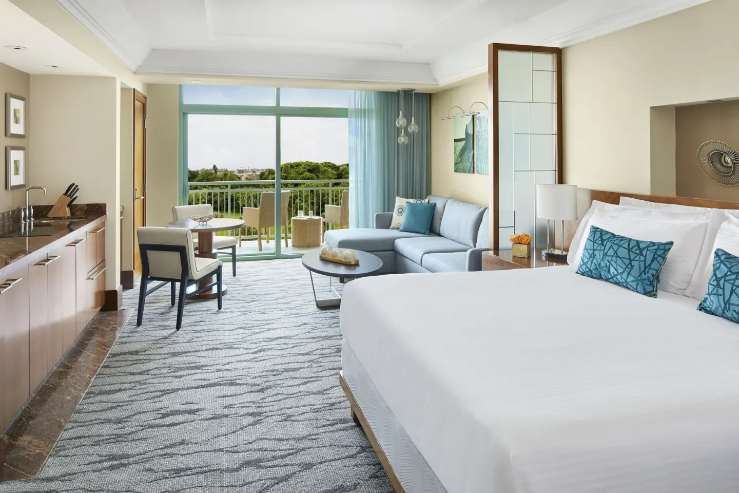 Studio Harbor View guest room with king bed, kitchenette, sofa, and balcony at The Reef at Atlantis.
