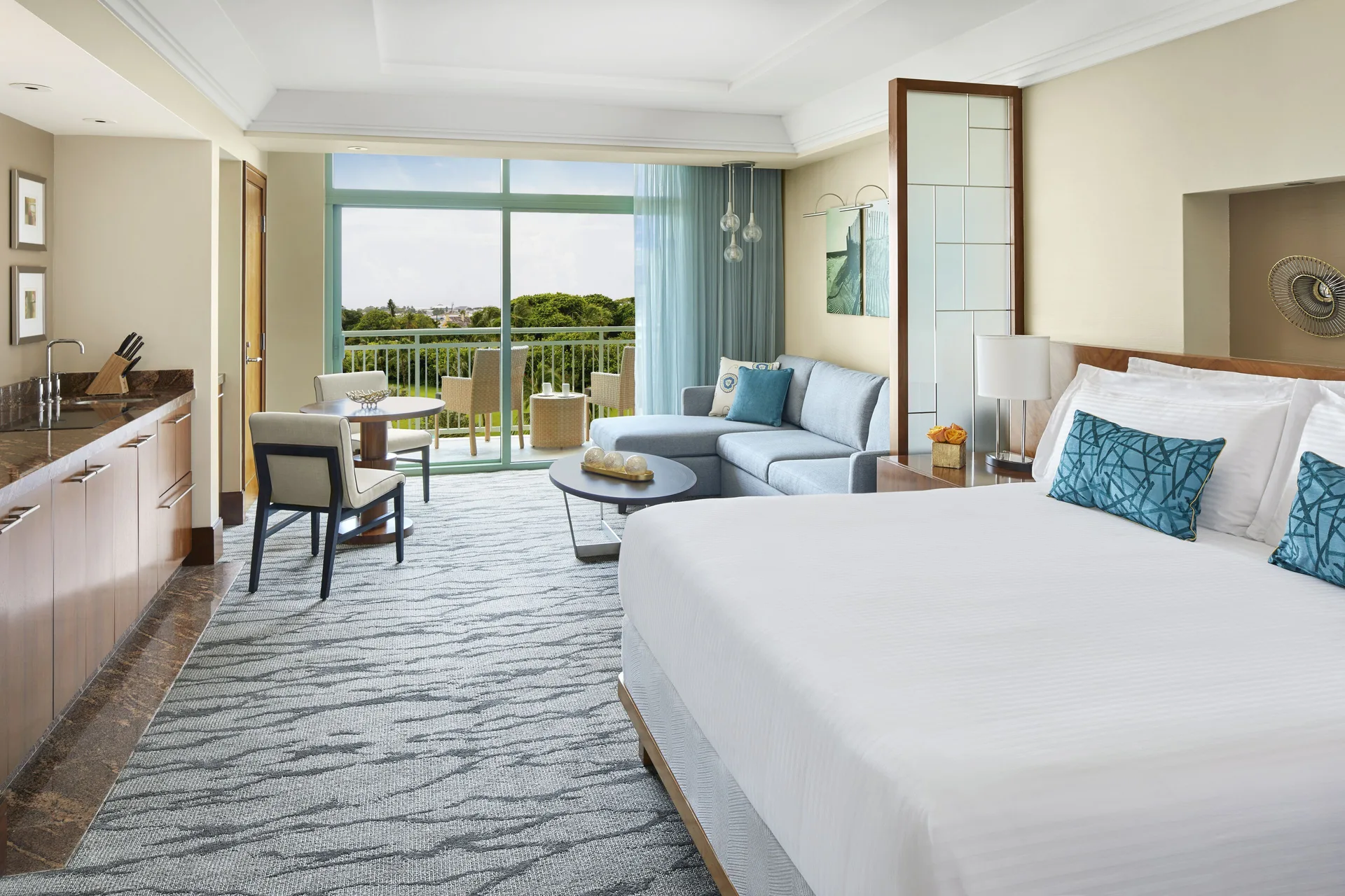 Studio Harbor View guest room with king bed, kitchenette, sofa, and balcony at The Reef at Atlantis.