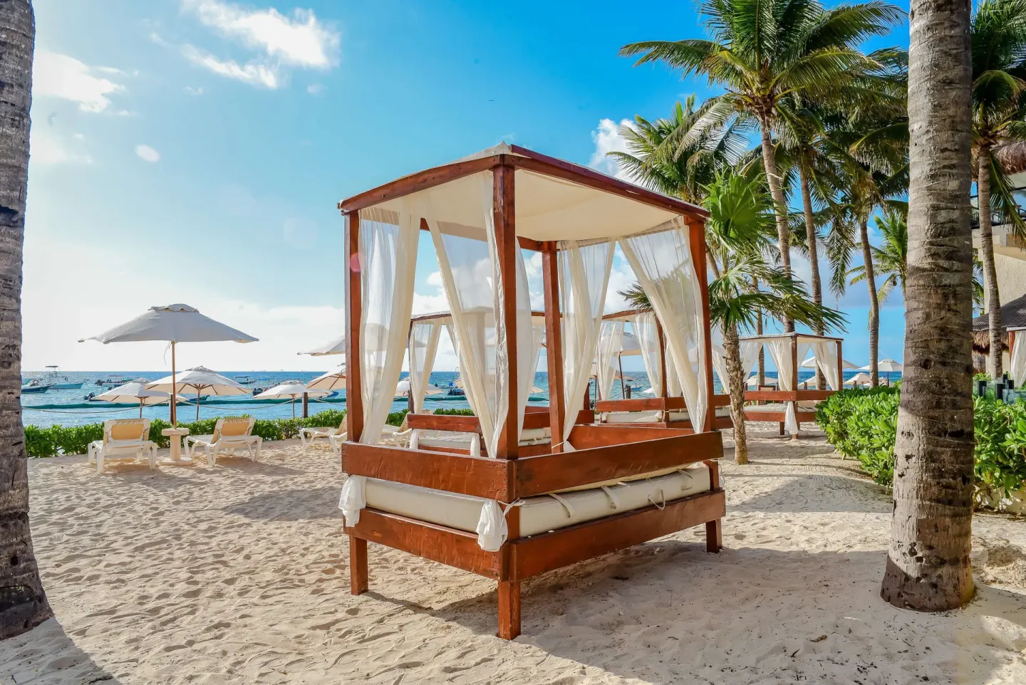 Beach cabana with white curtains on the sand at The Reef Coco Beach Resort & Spa.