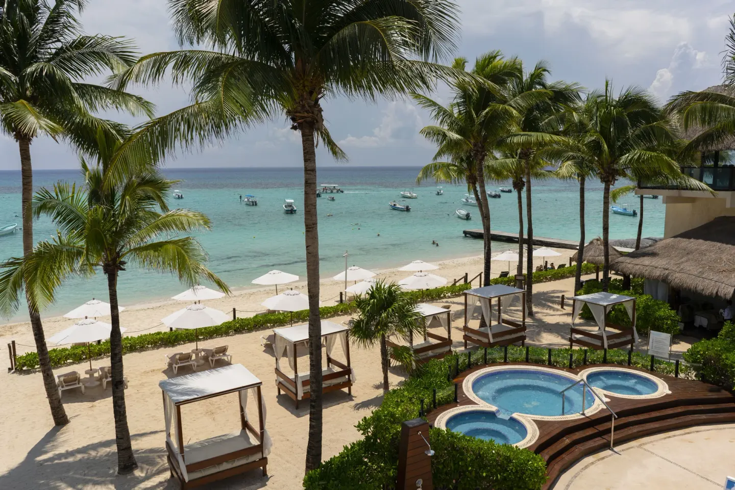 Beach cabanas, palms, and small pools at The Reef Coco Beach Resort & Spa.