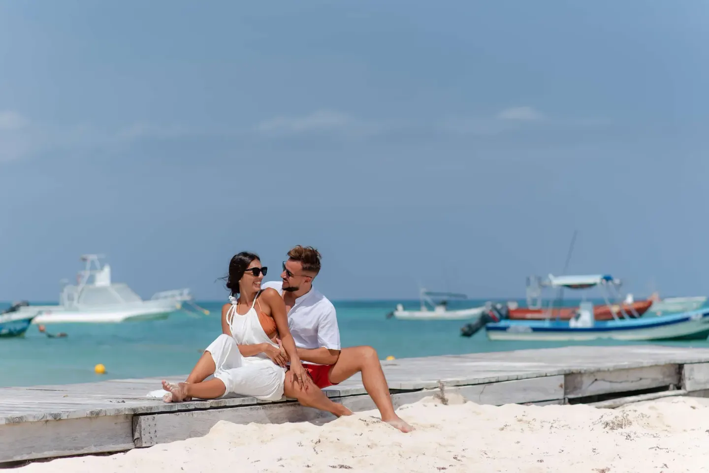Couple sitting on a beach pier at The Reef Coco Beach Resort & Spa.