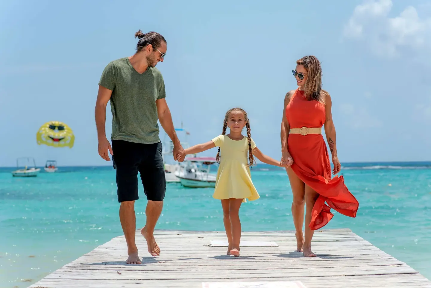 Family walking hand in hand on a pier at The Reef Coco Beach Resort & Spa.