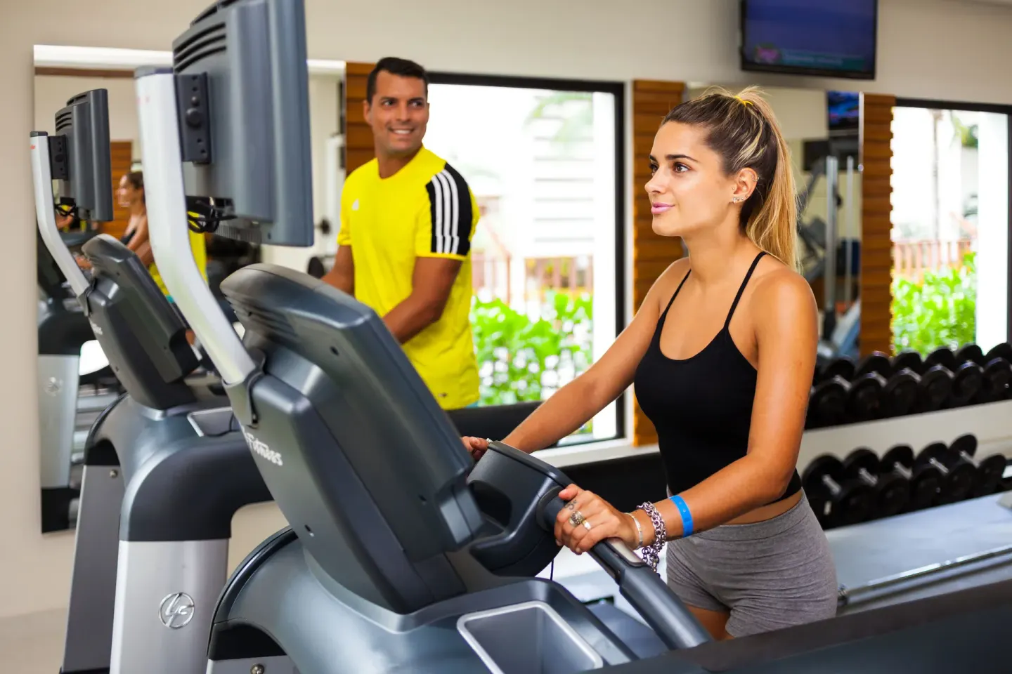 Guests using cardio equipment in the fitness room at The Reef Coco Beach Resort & Spa.
