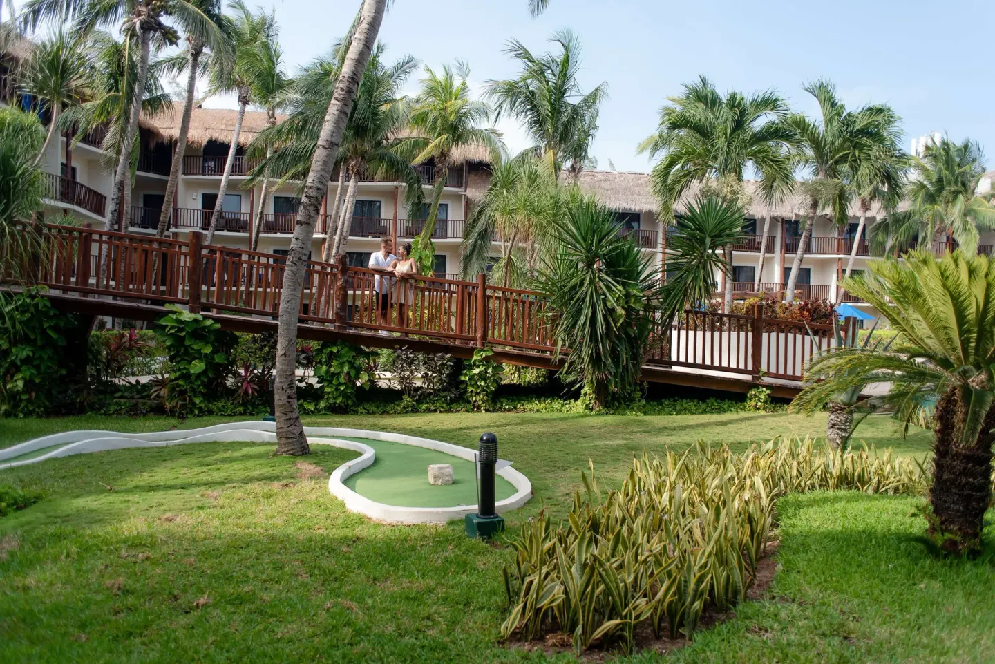 Tropical garden mini golf area and wooden bridge at The Reef Coco Beach Resort & Spa.