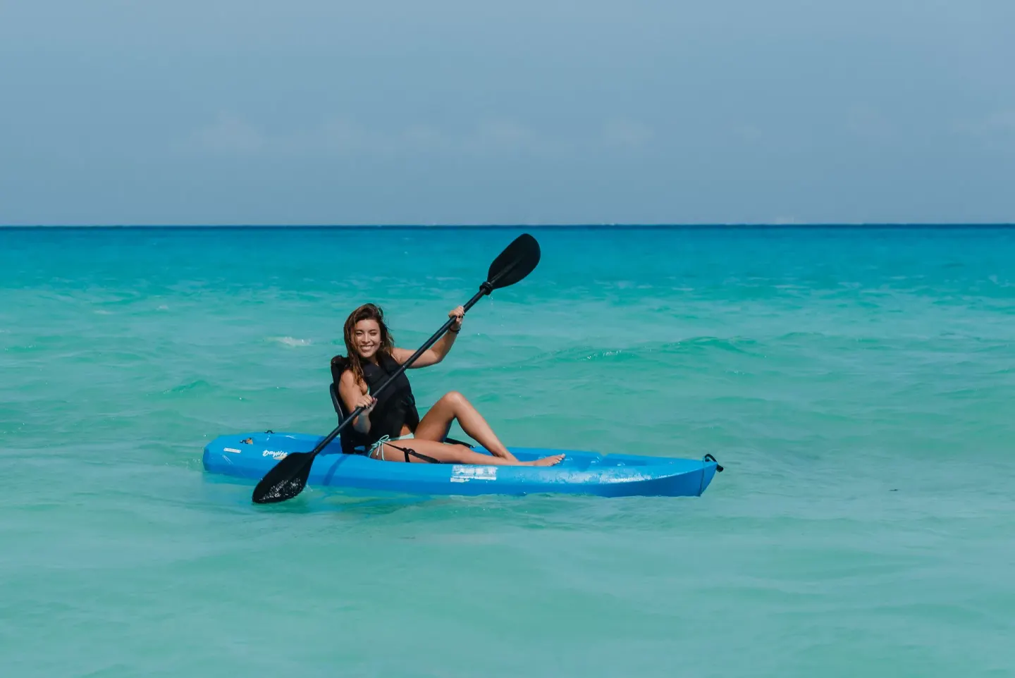 Guest kayaking on clear turquoise water at The Reef Coco Beach Resort & Spa.