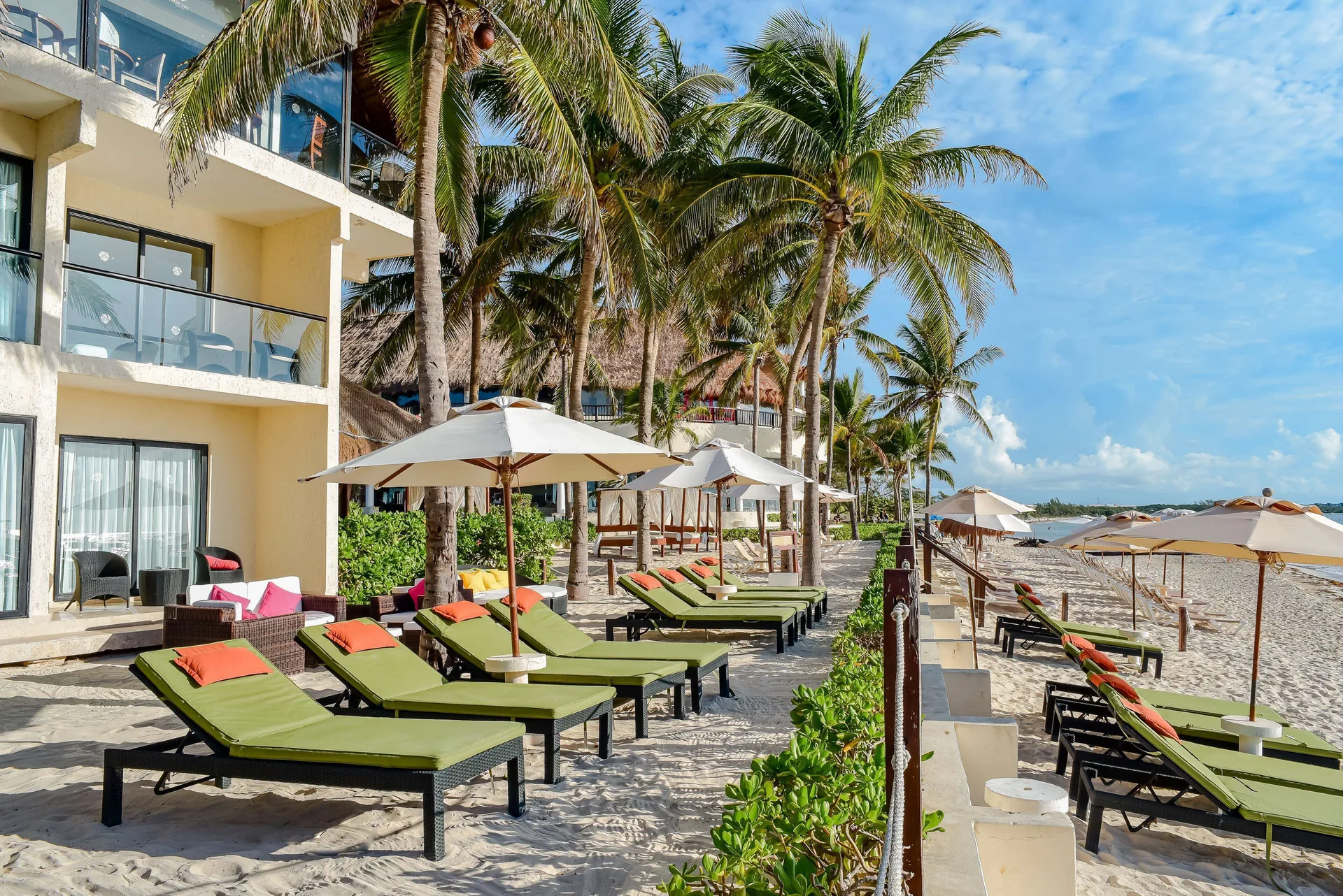 Green beach loungers beside oceanfront balconies at The Reef Coco Beach Resort & Spa.