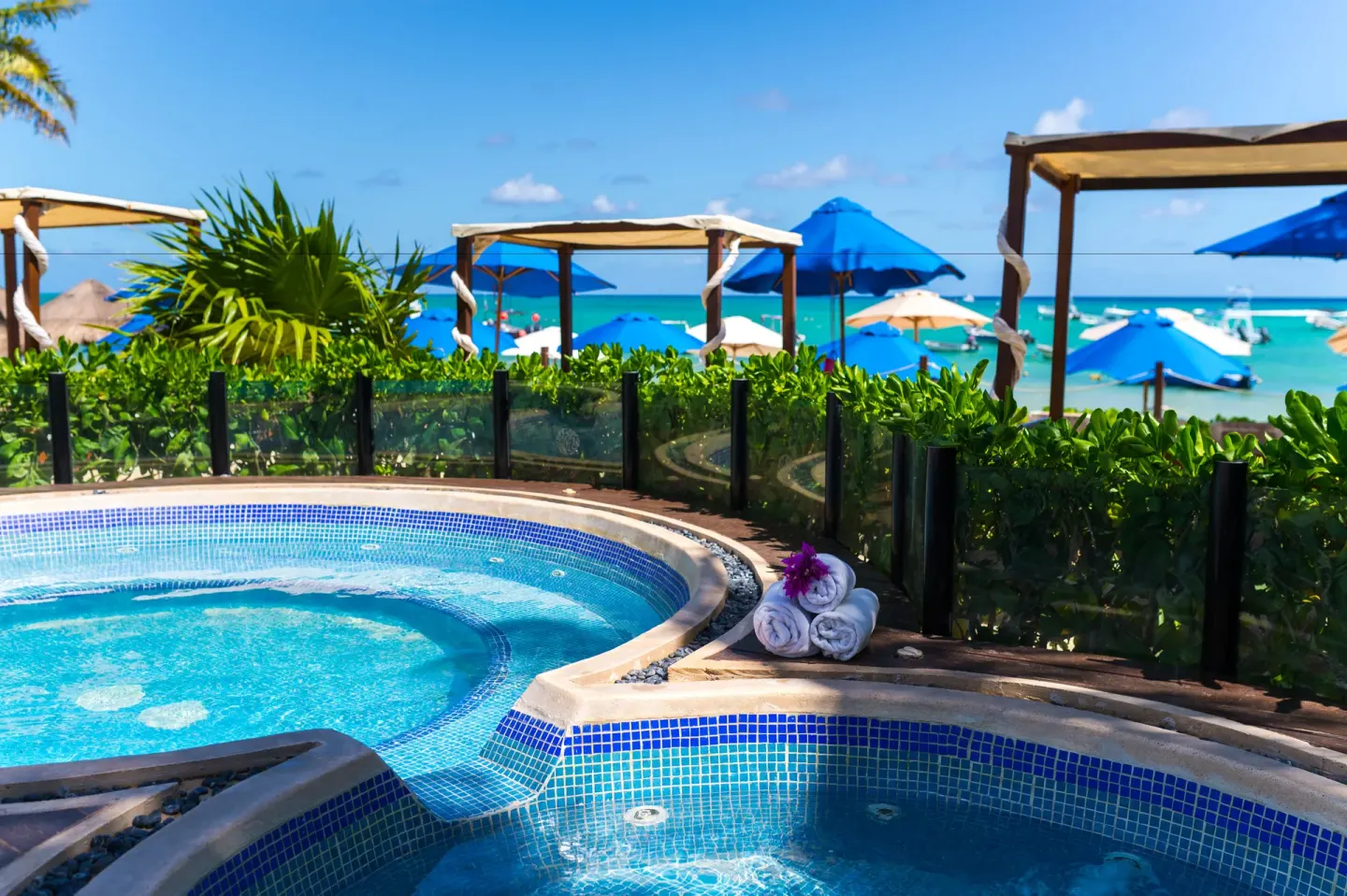 Outdoor whirlpools with towels, flowers, cabanas, and ocean beyond at The Reef Coco Beach Resort & Spa.