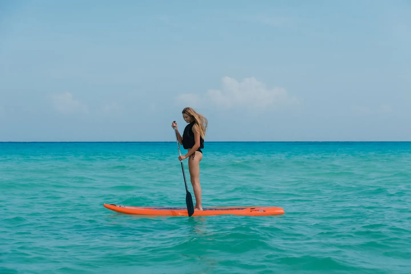 Paddleboarder on turquoise water at The Reef Coco Beach Resort & Spa.