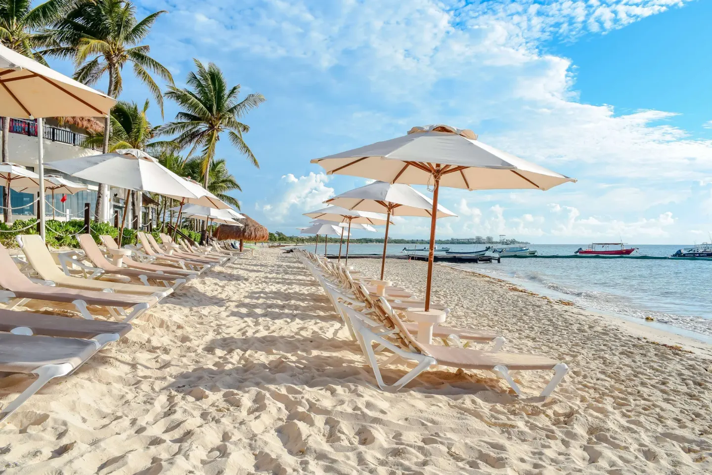 White umbrellas and loungers along the shoreline at The Reef Coco Beach Resort & Spa.