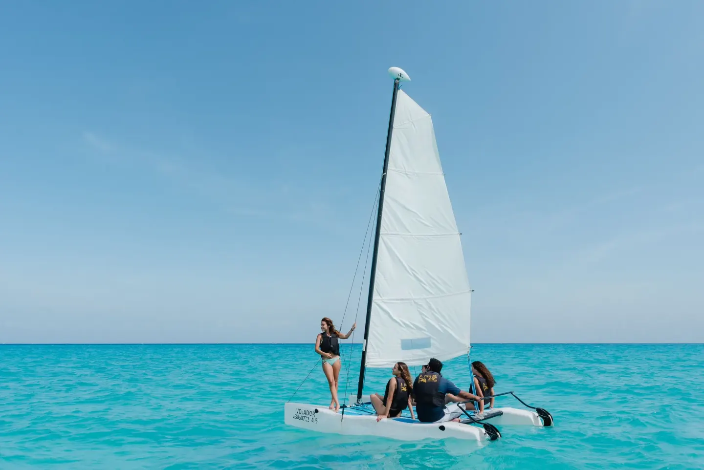 Small sailboat with guests on turquoise water at The Reef Coco Beach Resort & Spa.