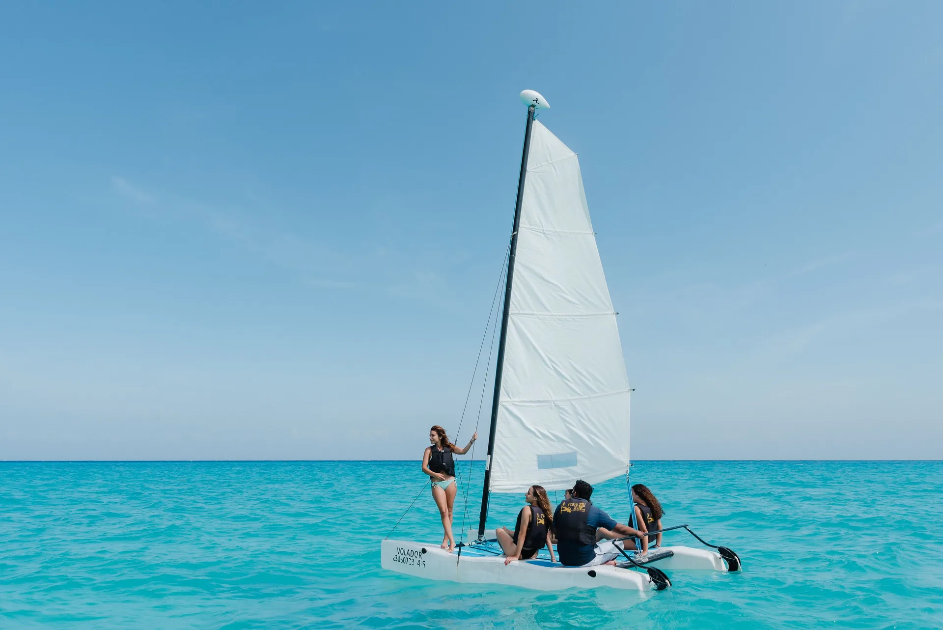 Small sailboat with guests on turquoise water at The Reef Coco Beach Resort & Spa.
