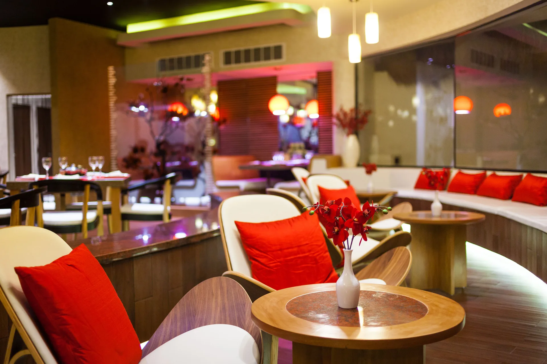 Lounge seating with red pillows and small tables at The Reef Coco Beach Resort & Spa.