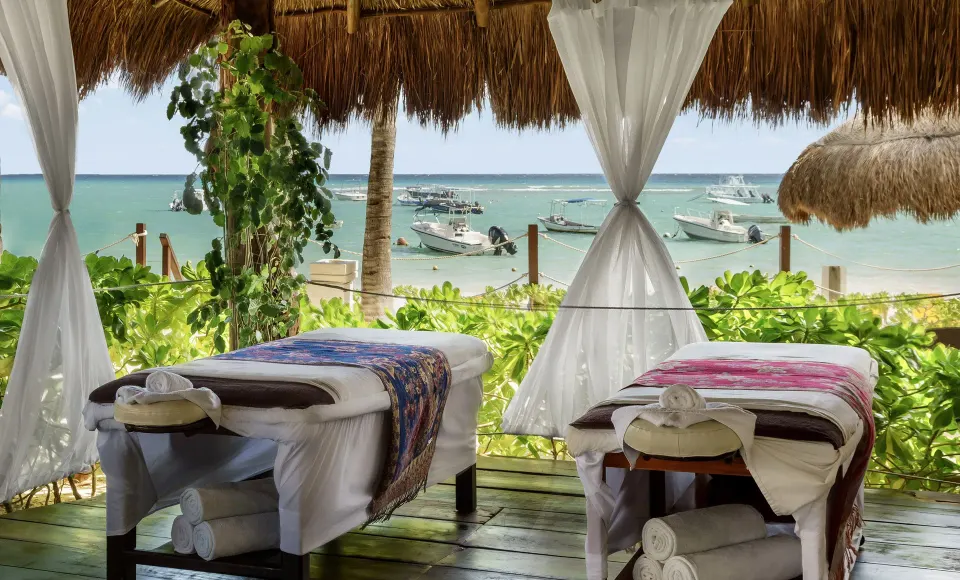 Open-air spa massage tables facing the beach at The Reef Coco Beach Resort & Spa.
