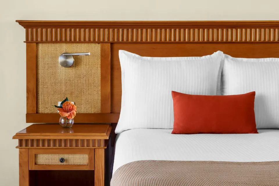 Superior Room Garden View bed detail with wood headboard at The Reef Coco Beach Resort & Spa.