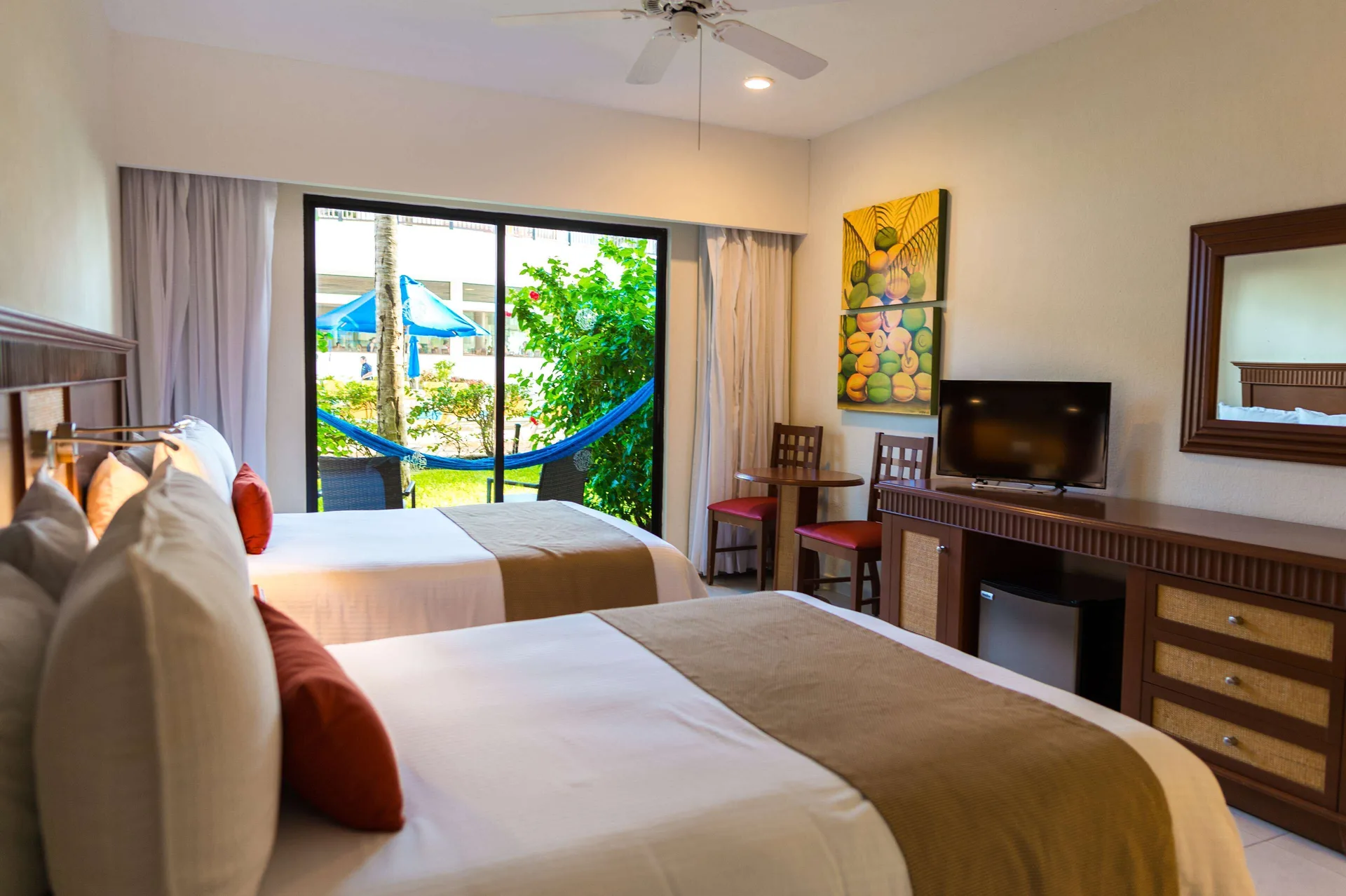 Superior Room Pool View with two beds and patio hammock at The Reef Coco Beach Resort & Spa.