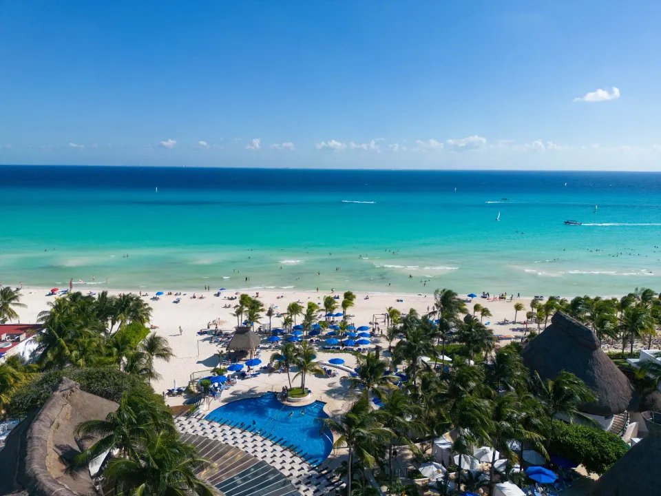 Aerial view of the resort pool area with beach and turquoise ocean at The Reef Playacar Beach Resort & Spa