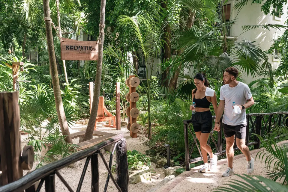 Couple walking a tropical garden path near a wellness area at The Reef Playacar Beach Resort & Spa