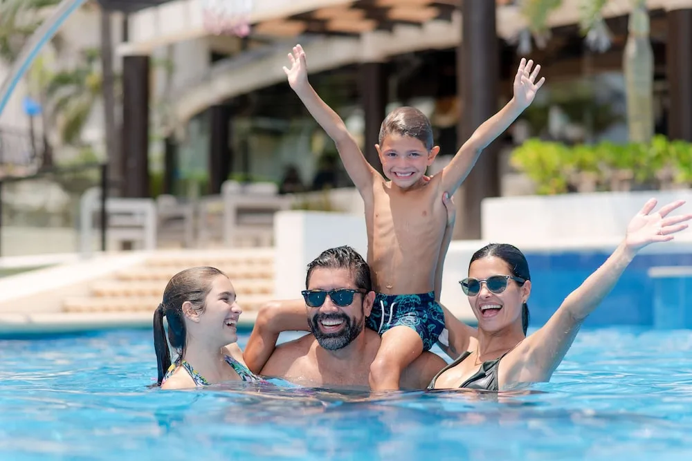 Family enjoying the resort pool together at The Reef Playacar Beach Resort & Spa