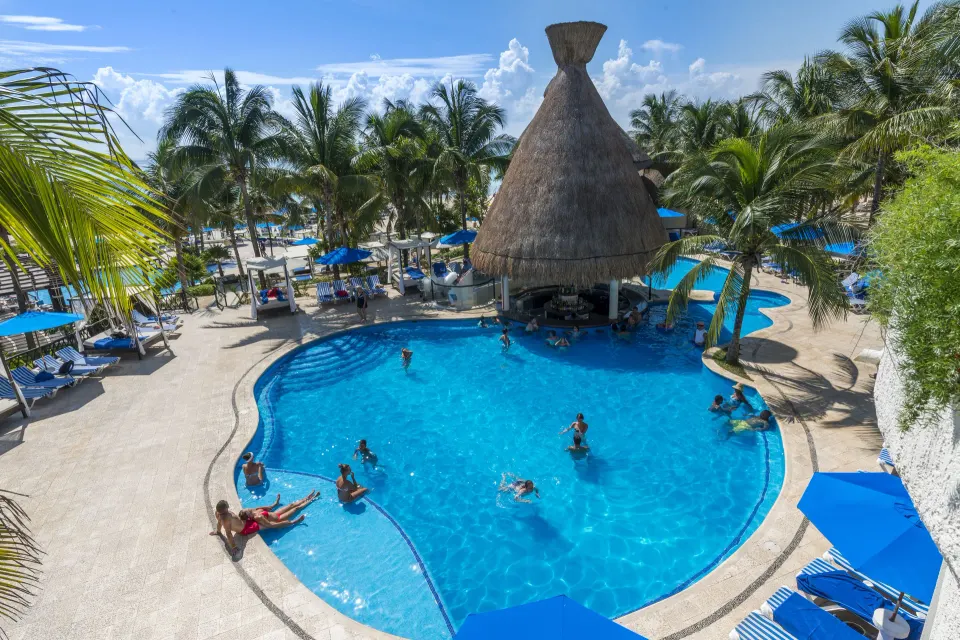 Overhead view of guests swimming in the freeform pool at The Reef Playacar Beach Resort & Spa